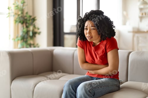 Preview: Worried young black woman sitting arms crossed and looking troubled