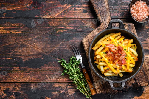 Preview: French fries with melted mix of cheddar cheese and bacon served in a pan. Dark wooden background