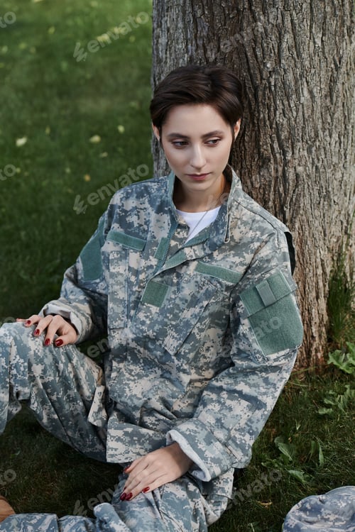 Preview: Young soldier in camouflage uniform reflects at homecoming under a tree in serenity