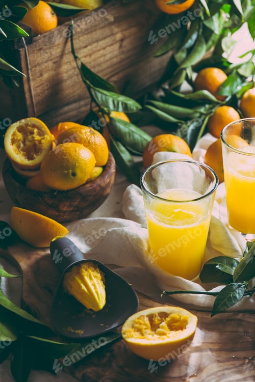 Preview: Orange juice, full box of orange fruits ant orange tree branches on table
