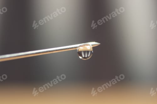 Preview: Shallow depth of field, close-up shot of a vaccine drop on a syringe needle.