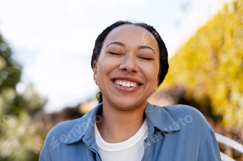 Preview: Happy young African American woman smiling with closed eyes outdoors, dental care concept