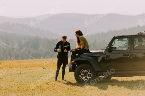 Preview: Young couple relaxing on a terrain vehicle hood at countryside