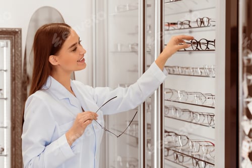 Preview: Smiling seller showing glasses assortment on the display shelf