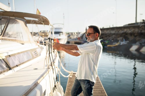 Preview: Senior Man Docking His Sailboat At Marina Using Rope Outside