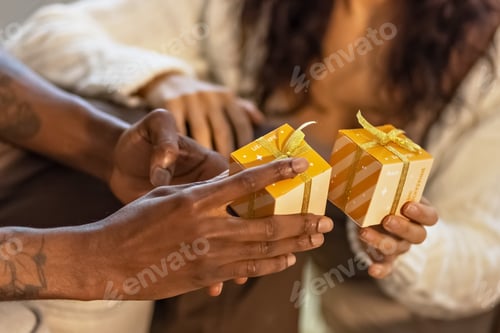 Vista previa: A happy couple of mulattoes exchange gifts with each other. Celebrating joint family events.