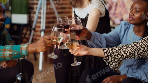 Preview: Close up shot of wine glasses being clinked at apartment party by friends celebrating