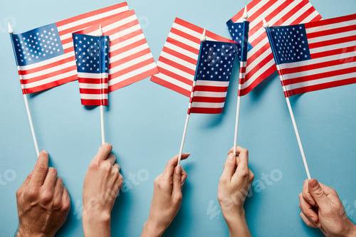 Preview: partial view of people holding american flags on blue background