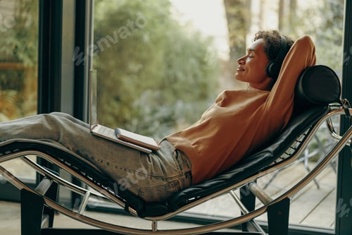 Preview: Smiling woman in headphones is listening music during break on work on laptop at home