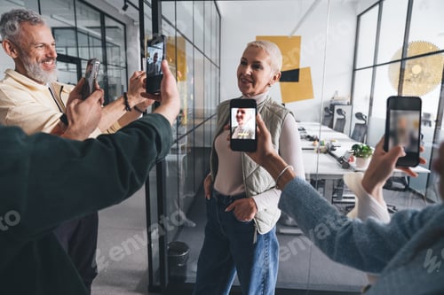 Preview: Cheerful colleagues taking photo of businesswoman in office
