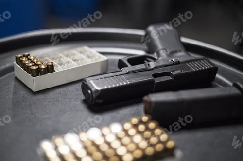 Preview: Handgun Resting on Tabletop with Magazine and Ammunition in Foreground
