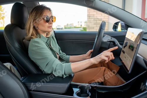 Preview: Young female driver pointing at display while choosing destination place