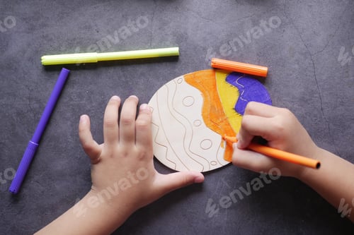 Preview: child girl drawing a easter egg on black background