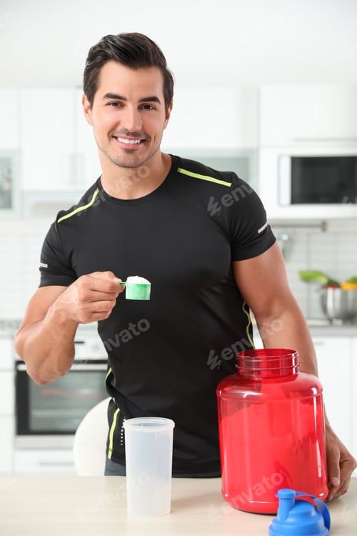 Preview: Young athletic man preparing protein shake in kitchen