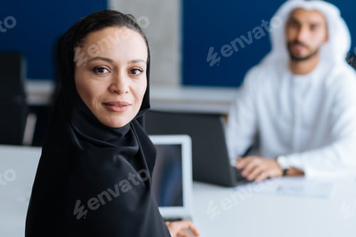 Preview: Handsome man and woman with traditional clothes working in an office of Dubai