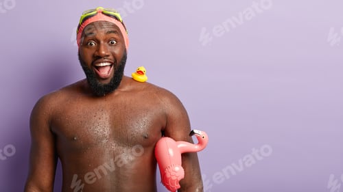 Preview: Horizontal shot of delighted sporty male swimmer with naked torso, waterdrops on skin, has fun at be