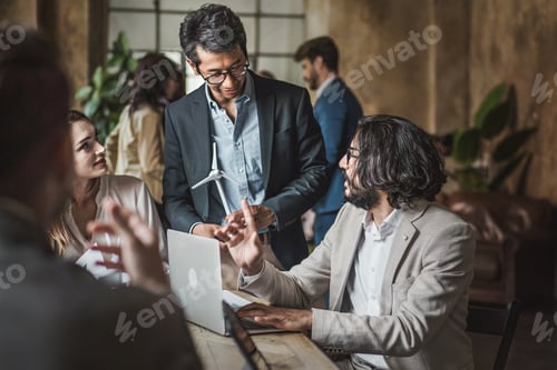 Preview: Businesspeople discussing a renewable project with windmills