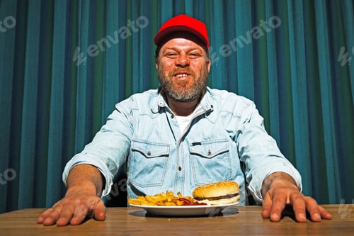 Preview: Man With Beard Eating Fast Food Meal. Enjoying French Fries And A Hamburger. Trucker With Red Cap.