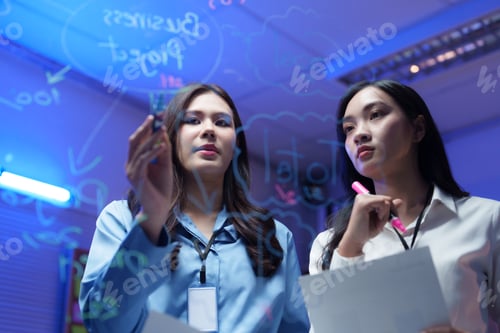 Preview: Businesswomen planning project, brainstorming and writing on transparent board