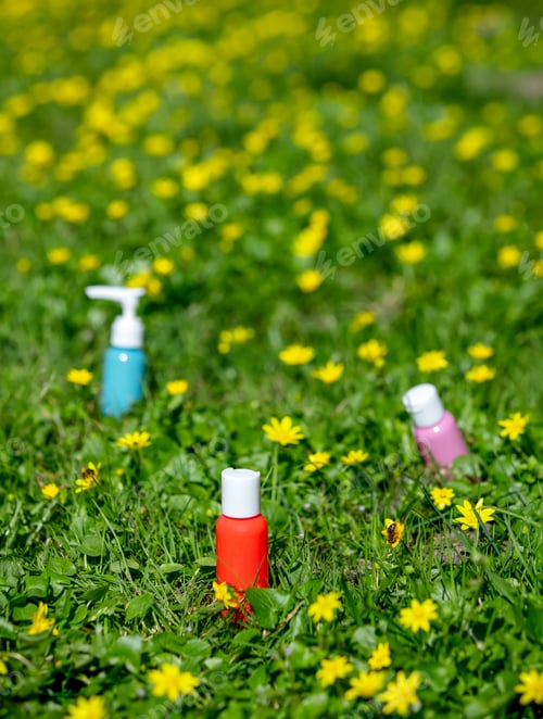Preview: Red and blue bottles for cosmetic on meadow with yellow flowers in spring time