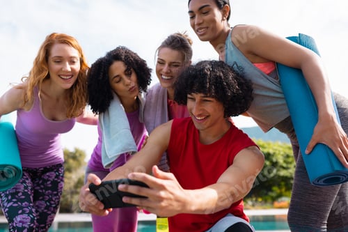 Preview: Diverse friends using smartphone and holding yoga mats in garden