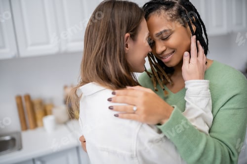 Preview: lesbian african american woman with engagement ring hugging girlfriend on valentines day