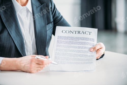 Preview: partial view of businesswoman sitting at workplace and pointing at contract