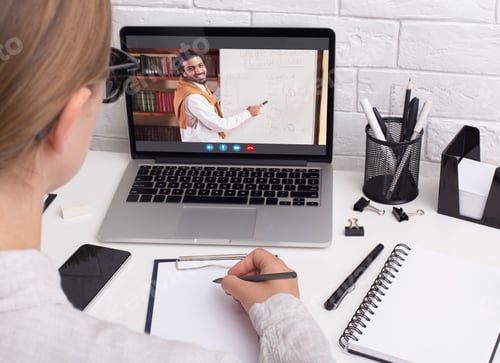 Preview: Young woman in glasses writing notes while attending webinar