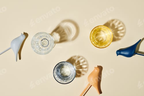 Preview: Flatlay of three glasses containing water, their shadows and small toy birds