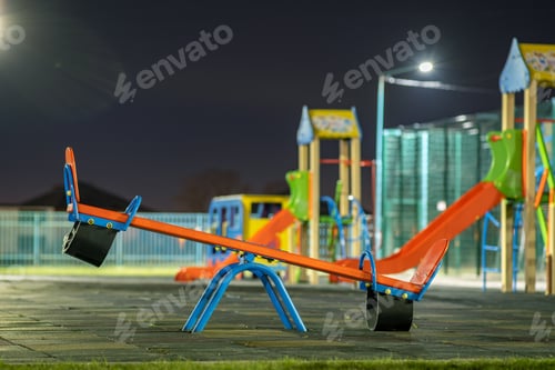 Preview: Seesaw swing in preschool yard with soft rubber flooring at night.