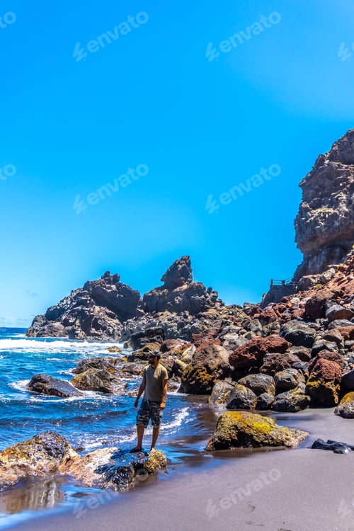 Preview: A young tourist enjoying summer by the sea on some rocks in Playa de Nogales