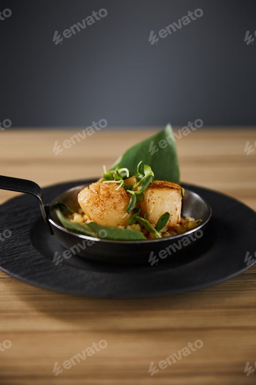 Preview: delicious grilled scallops with green leaves and microgreens on wooden table on black background