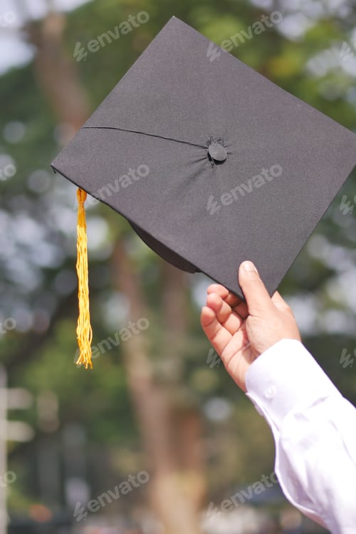 Preview: Student hold hats in hand during commencement success on yellow background