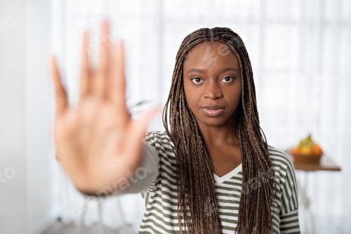 Preview: Serious young black woman showing stop gesture