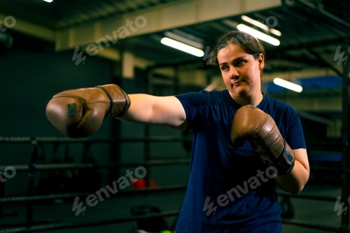 Preview: portrait of a woman in boxing gloves posing in a cheeky and competitive fight in a boxing ring