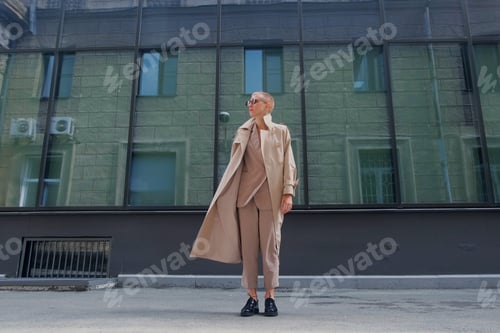 Preview: A Woman With Short Hair In Gray Coat And Glasses Dancing, Walking, Smiling On A City Street.