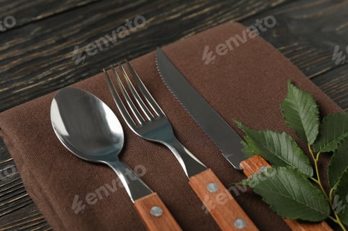 Preview: Napkin, fork, spoon, knife and leaf on wooden background
