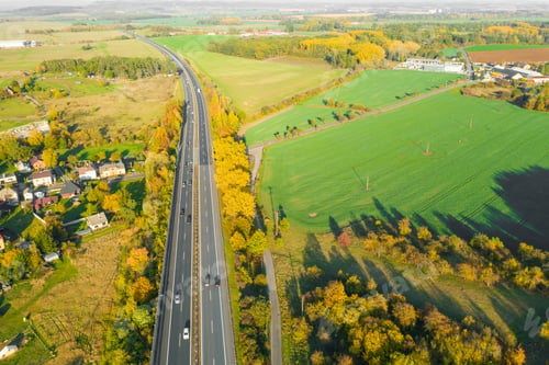 Preview: Highway between Autumn forest and cultivated ground with yellow trees at sunset in autumn. Aerial