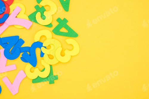 Preview: Flat lay of colorful wooden numbers on a yellow surface - space for text