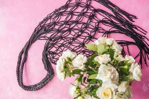 Preview: Black string net bag with white roses on pink background