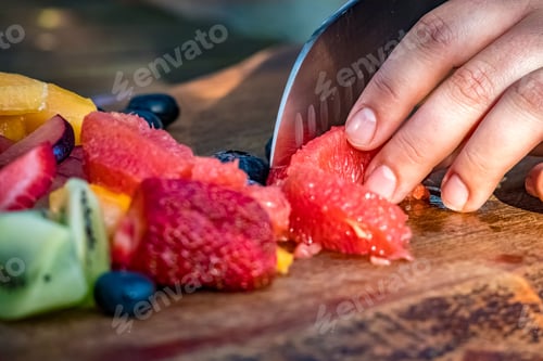 Preview: Hand of a chef slicing fresh fruits on a wooden board