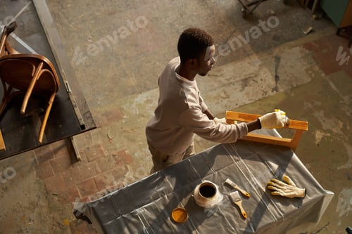 Preview: Top view of young black man doing furniture restoration project