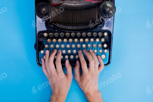 Preview: Human hands typing on vintage type writer machine - top view.
