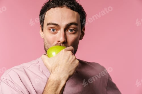 Preview: Happy handsome unshaven guy eating green apple