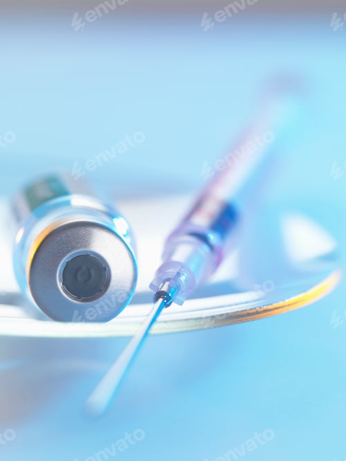 Preview: Vaccine and hypodermic syringe sitting on a glass dish