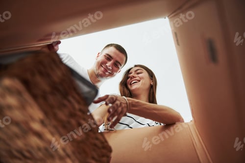 Preview: Two people looks down into the box. Conception of moving