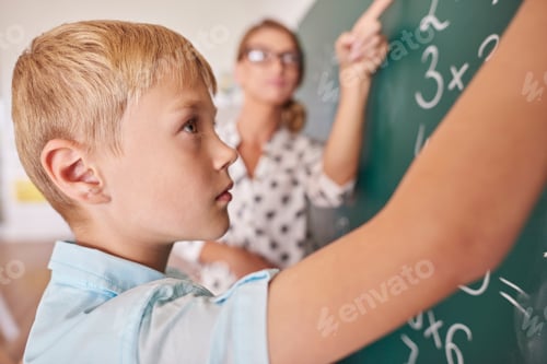 Preview: Student boy doing math problem on chalkboard