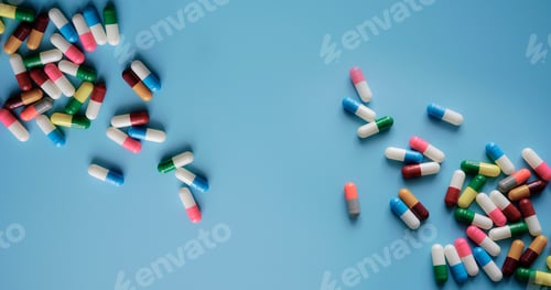 Preview: Top view colorful antibiotic capsule pills on blue background. Online pharmacy banner. World Health