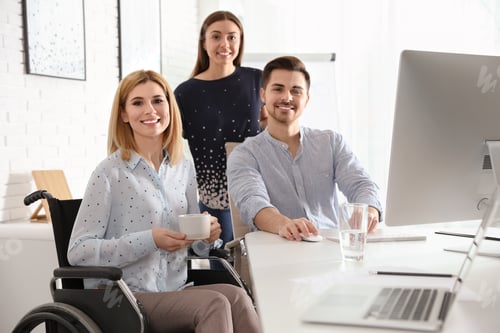Preview: Portrait of woman in wheelchair with her colleagues at workplace