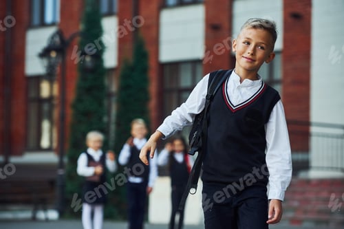 Preview: Group of kids in school uniform posing to the camera outdoors together near education building